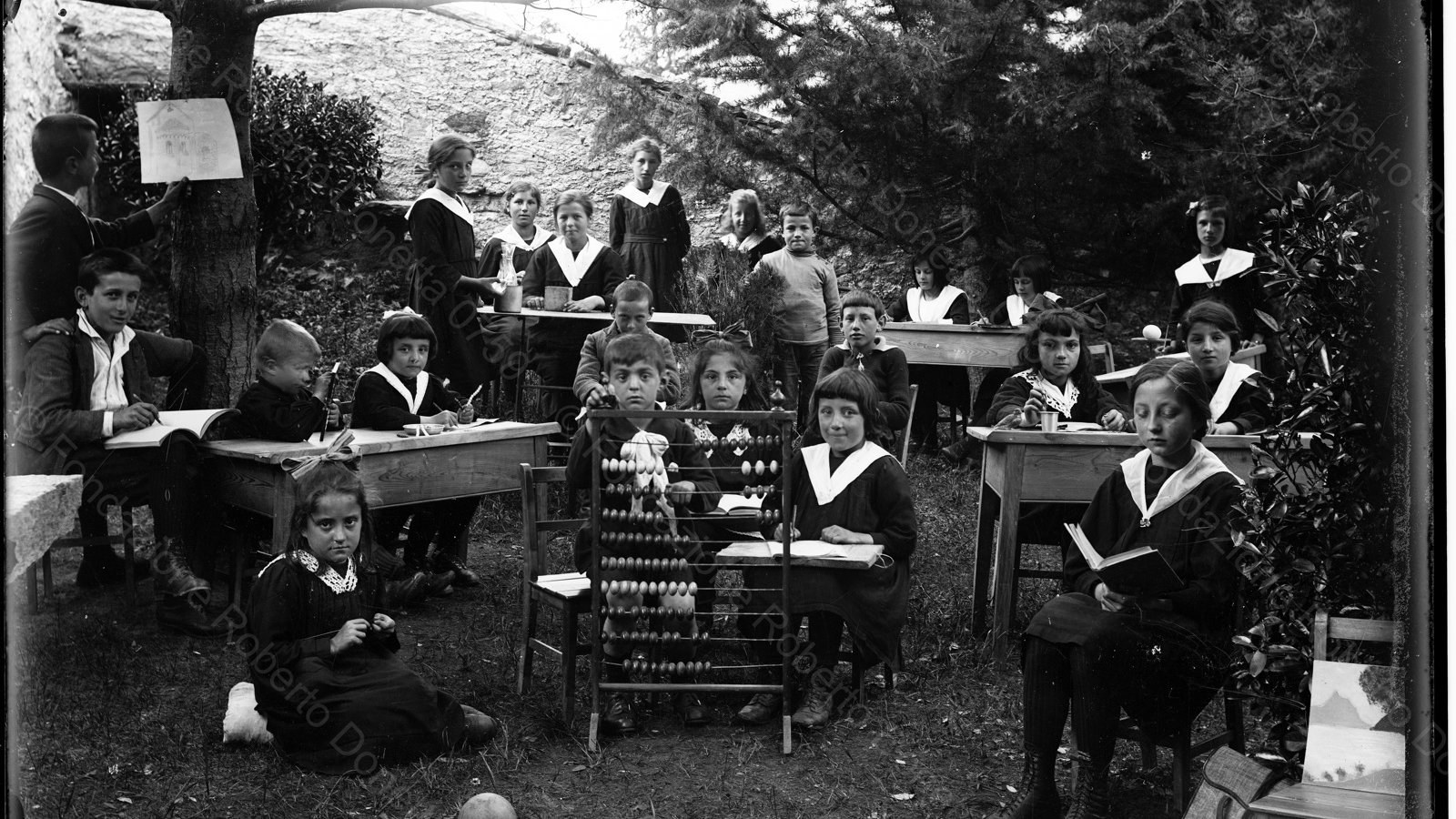 Eine Schulklasse um 1870 im Tessin draussen im Freien mit Pulten